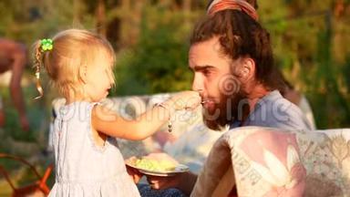 一个小女孩用勺子喂她爸爸。 夏天晚上在村里。